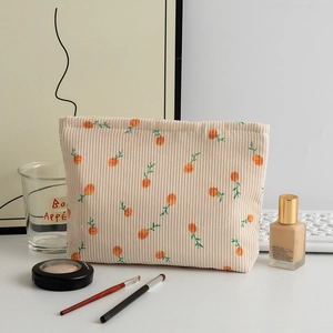 Close-up of floral corduroy cosmetic bag featuring orange embroidery and soft texture