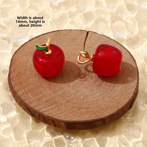 Detail of red apple glass charms with gold metal stems and green leaf accents