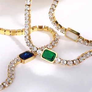 Macro shot of 18K gold plated tennis chains with emerald green and blue zircon gemstones