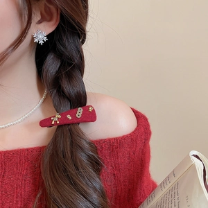 Detail of red wool horse hair clip with pearl necklace and snowflake stud earrings