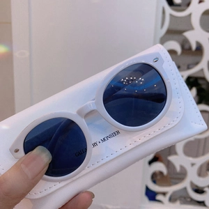 Detailed macro view of white round children sunglasses and branded leather texture case
