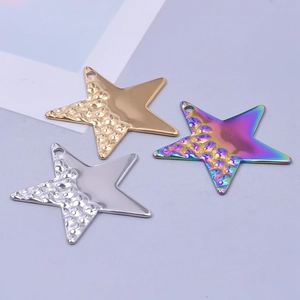 Détail macro de trois pendentifs étoile en or, argent et arc-en-ciel au fini martelé