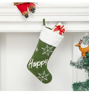 Close-up of a green felt Christmas stocking with white snowflake and Happy embroidery