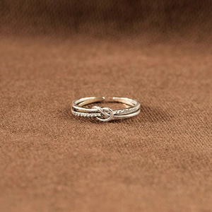 Détail macro d'une bague double nœud en argent S925 avec zircons sur tissu brun