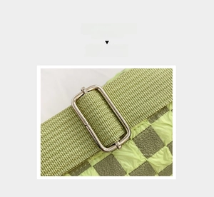 Detail view of adjustable green nylon shoulder strap and silver metal buckle on checkered bag