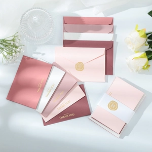 Detail view of pink and white cards with gold stamped Thank You and rose wax seals