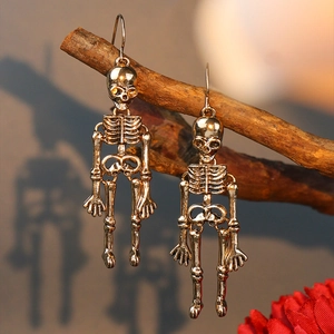 Artistic close-up of gold skeleton earrings hanging on a branch with warm lighting
