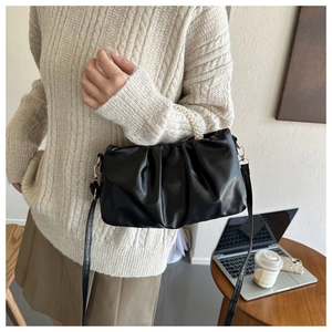 Detail of black pleated cloud bag with pearl handle on model in office setting