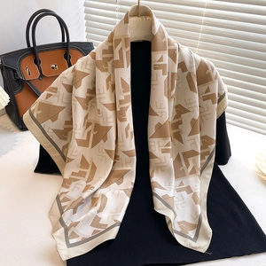 Gros plan d'un foulard en soie beige et marron à motifs géométriques sur un support