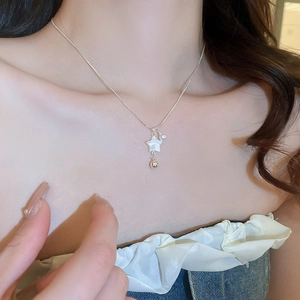 Detail of silver chain necklace featuring star pendant, pearl, and gold bead on neck