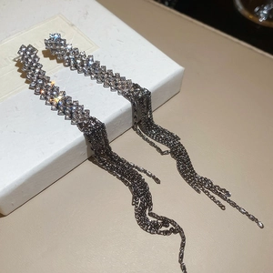 Detailed view of silver tassel earrings with sparkling rhinestones on a white gift box