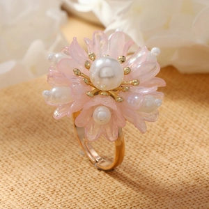 Macro shot of handmade pink floral ring with pearls and adjustable gold band