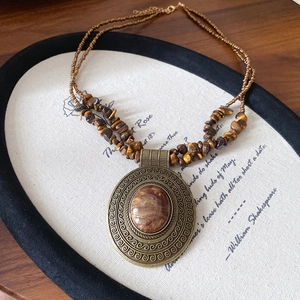Close-up of vintage bronze flower pendant with tiger eye stone on double-strand wooden beads