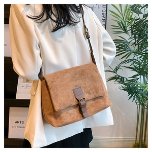 Detailed texture of brown matte suede crossbody bag with metal buckle and shoulder strap