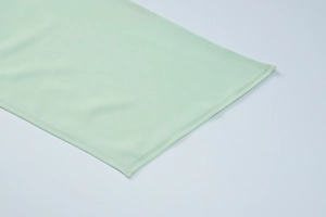 Gros plan sur le tissu vert clair de la robe montrant les détails de couture double aiguille