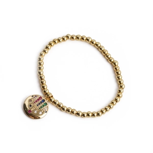 Detailed macro view of gold beaded bracelet featuring a colorful gemstone palm pendant