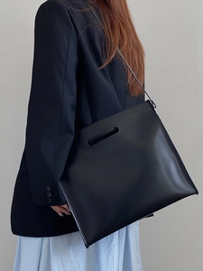 Chic large black leather tote bag worn by a model in professional office attire