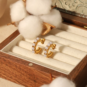 Boucles d'oreilles créoles dorées 18K avec perles sur un coffret à bijoux rétro