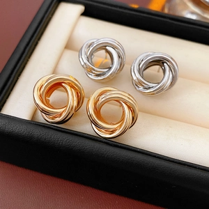 Gros plan de boucles d'oreilles nœuds or et argent sur un coussin de boîte à bijoux