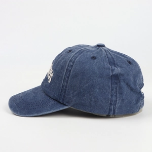 Close-up of washed blue denim baseball cap with white embroidery and curved brim