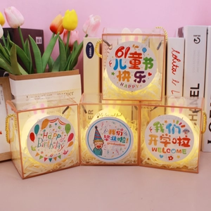 Close-up of clear gift boxes with LED string lights and festive stickers for parties