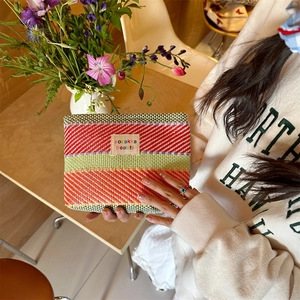 Close-up of a vibrant striped woven cosmetic bag with natural texture and chic label