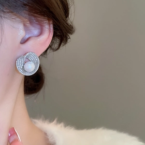 Macro view of irregular pearl stud earrings with zircon inlay on model's ear