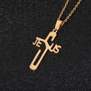 Vue macro détaillée du pendentif croix en acier doré avec lettrage ajouré JESUS
