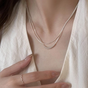 Detail of silver double-layer layered necklace featuring beads on smooth snake chain