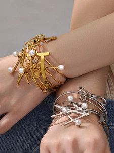 Close-up of geometric 18k gold and silver bangles with elegant pearl accents on wrist