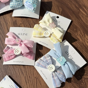 Detailed set of blue and pink plaid fabric hair bows with buttons on a wooden background