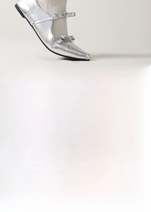 Detail of white wavy jacquard socks paired with silver metallic Mary Jane flats and bows