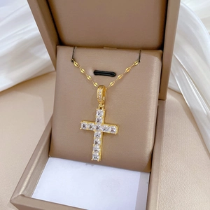 Detailed macro of gold cross pendant necklace featuring square cubic zirconia stones