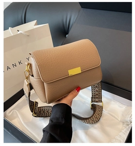Détail du sac bandoulière en cuir grainé marron avec sangle jacquard et fermoir doré