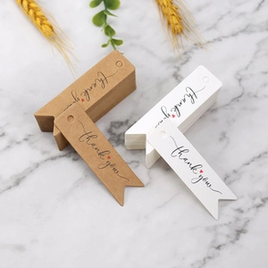 Macro detail of brown kraft and white swallowtail Thank You gift tags on marble