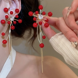 Macro shot of red starburst tassel earrings with zircon center and gold chain fringe