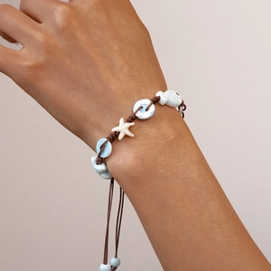 Detail of hand-woven bracelet featuring ceramic stars, flowers and adjustable wax cord