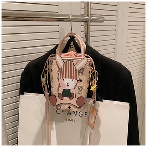 Pink cartoon bucket bag with rabbit detail and bear pattern on black blazer background