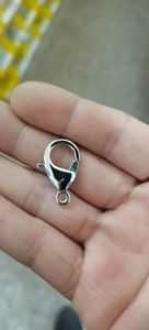 Primo piano di una chiusura a moschettone in acciaio al titanio lucido sulla mano