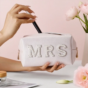 Light pink PU leather bridal makeup bag with pearl MRS letter held by a model