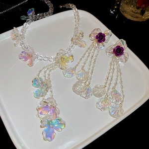 Detail view of handmade flower fringe necklace and purple rose earrings on white tray