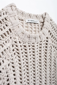 Detail of chunky knit cream sweater showing neckline texture and intricate openwork pattern