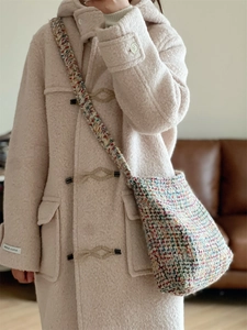 Close-up of multicolor tweed knit crossbody bag paired with a beige wool duffle coat