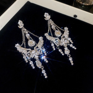 Detail of silver drop earrings with shimmering crystals, wing shapes and fringe tassels