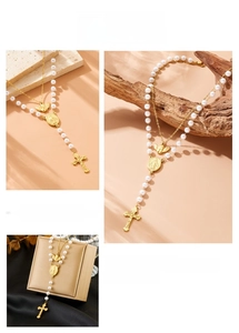 Detail of double-layer necklace with angel pendant, pearls, cross and oval medal