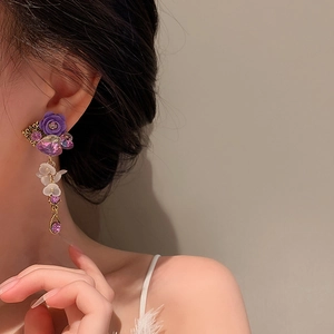 Close-up of purple crystal flower earrings with silver needles on model's ear