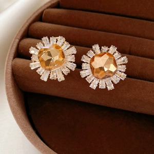 Détail des boucles d'oreilles tournesol dorées champagne dans un écrin en velours luxueux