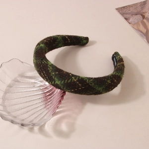 Detail of green and brown plaid tweed headband resting on a decorative glass shell tray