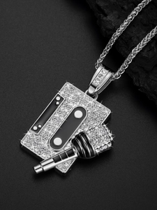 Macro detail of iced-out silver hip hop cassette tape and microphone pendant with crystals