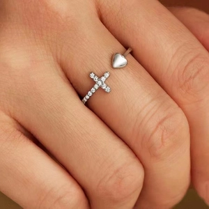 Detail of silver cross and heart open ring with micro-pave crystals on a female finger